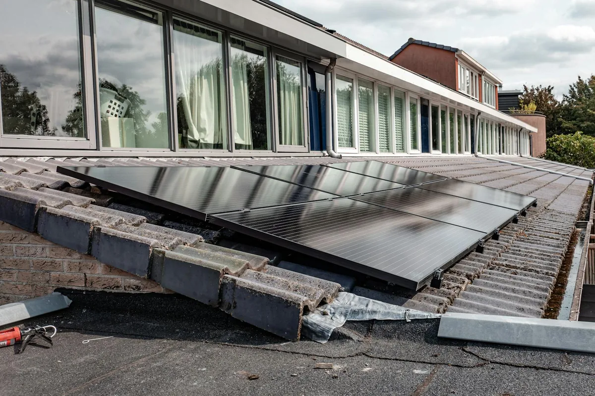 Installation de panneaux solaires bifaciaux noirs modernes en bi-verre sur une toiture résidentielle, vue de profil
